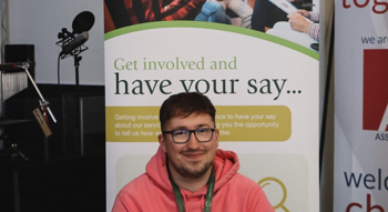Neighbourhood Officer Jack sits smiling with cake and a banner that says 'get involved'.